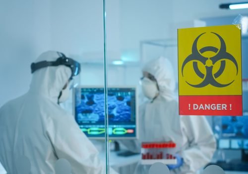Worried scientists in ppe suit talking behind the glass wall working in danger area of lab. Chemists developing vaccine using tablet examining virus evolution researching for treatment against covid19